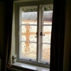 White aluminium secondary glazing face fixed into existing timber window.