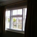 White aluminium secondary glazing face fixed into existing timber window.