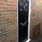 Black GRP Composite front door with a white uPVC outerframe and chrome furniture