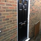 Black GRP Composite front door with a white uPVC outerframe and chrome furniture