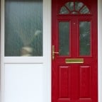Red GRP Composite front door with a white uPVC outerframe, sidelight and gold colour furniture