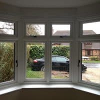 White woodgrain A-rated uPVC window. Liniar fully sculptured framing with dummy casements for equal sight lines and black antique style monkey tail handles