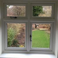 White woodgrain A-rated uPVC window. Liniar fully sculptured framing with dummy casements for equal sight lines and black antique style monkey tail handles