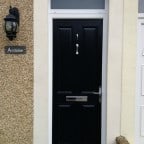 Black GRP composite front door with sandblasted (satin) glass in top light and a chrome pony tail knocker, letterbox and handle.   (2)