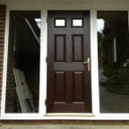 Darkwood GRP composite front door with white a uPVC outerframe glazed with clear toughened glass