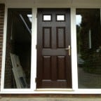 Darkwood GRP composite front door with white a uPVC outerframe glazed with clear toughened glass